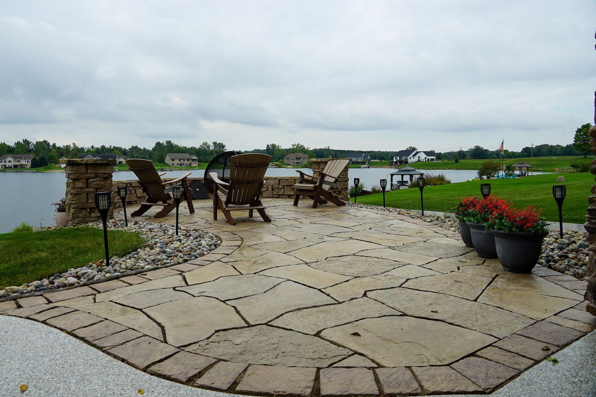 A patio with chairs and potted flowers overlooking a lake