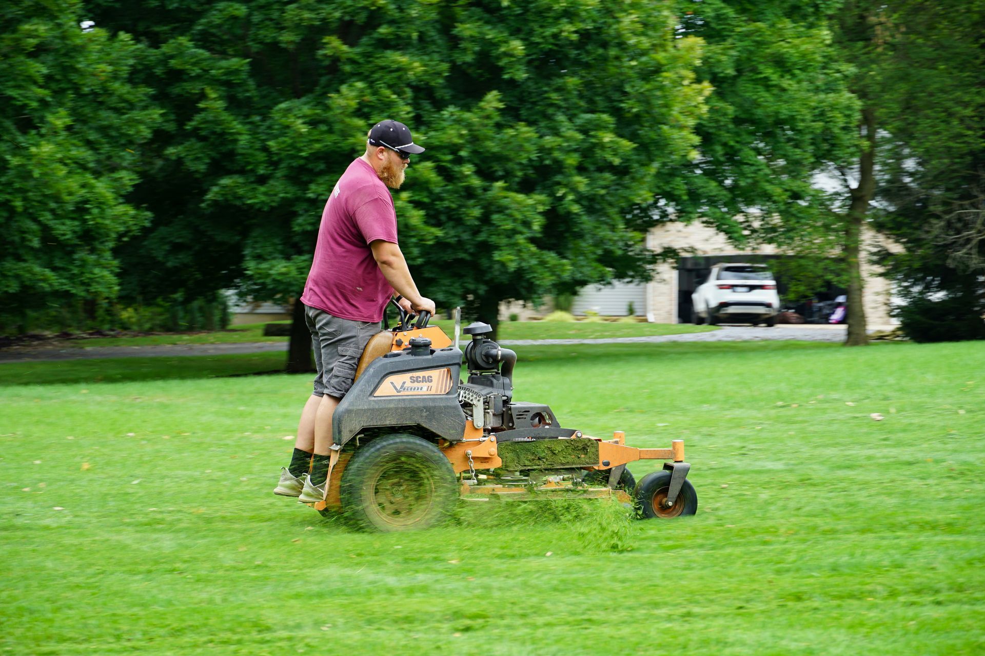 A man is riding a lawn mower on a lush green field.