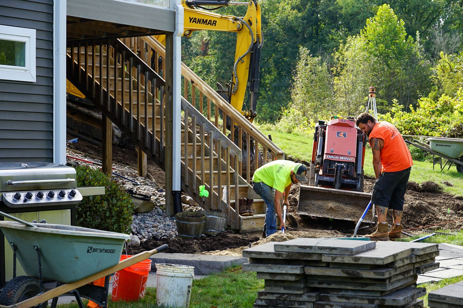 A group of men are working on a patio in front of a house.