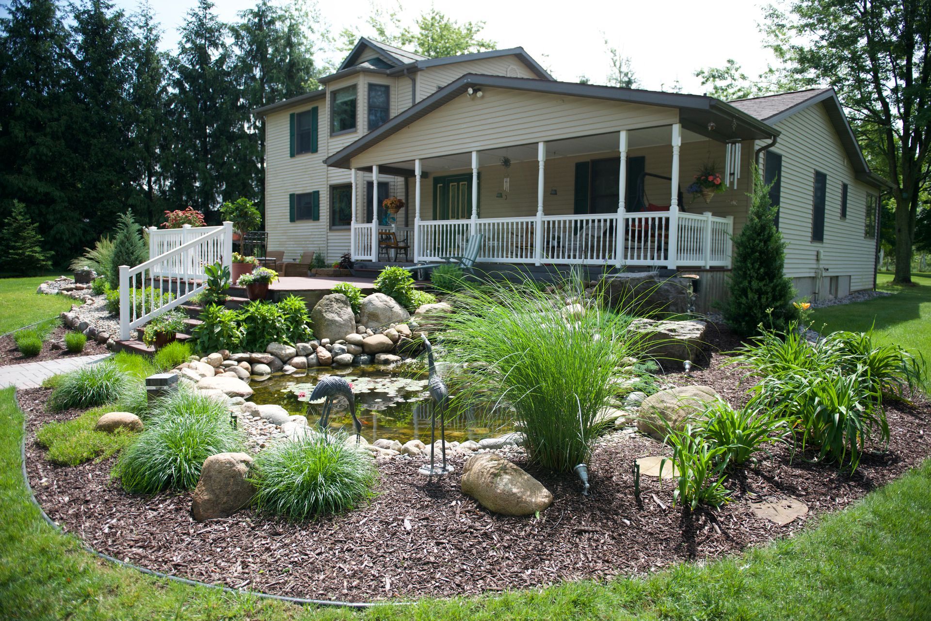 A house with a porch and a pond in front of it