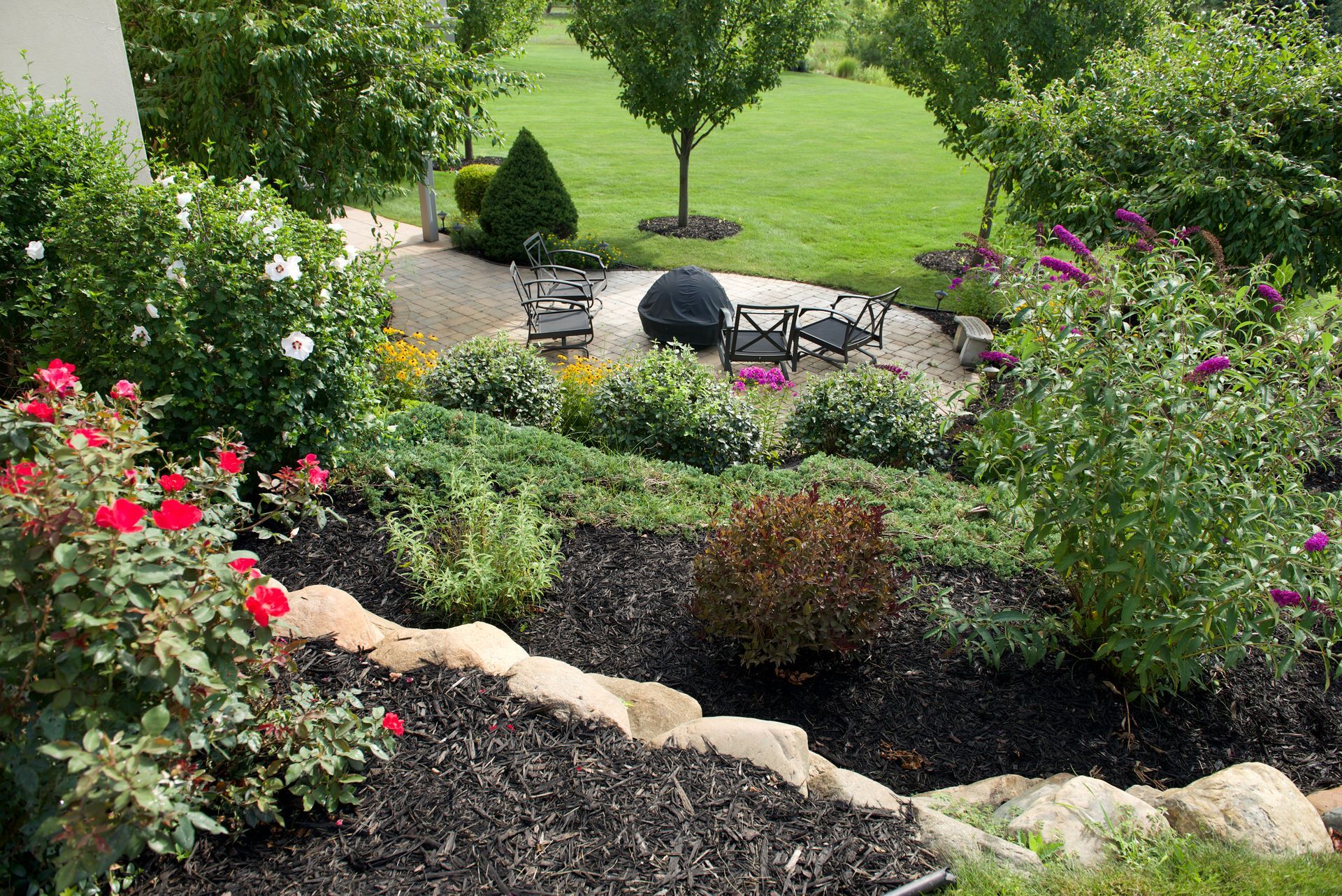 A lush green garden with a fire pit in the middle of it