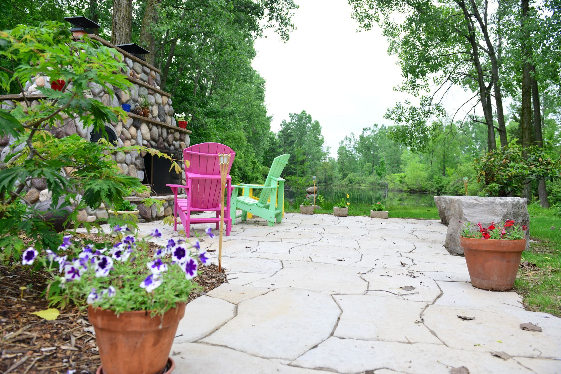 A patio with flowers and chairs and a fireplace