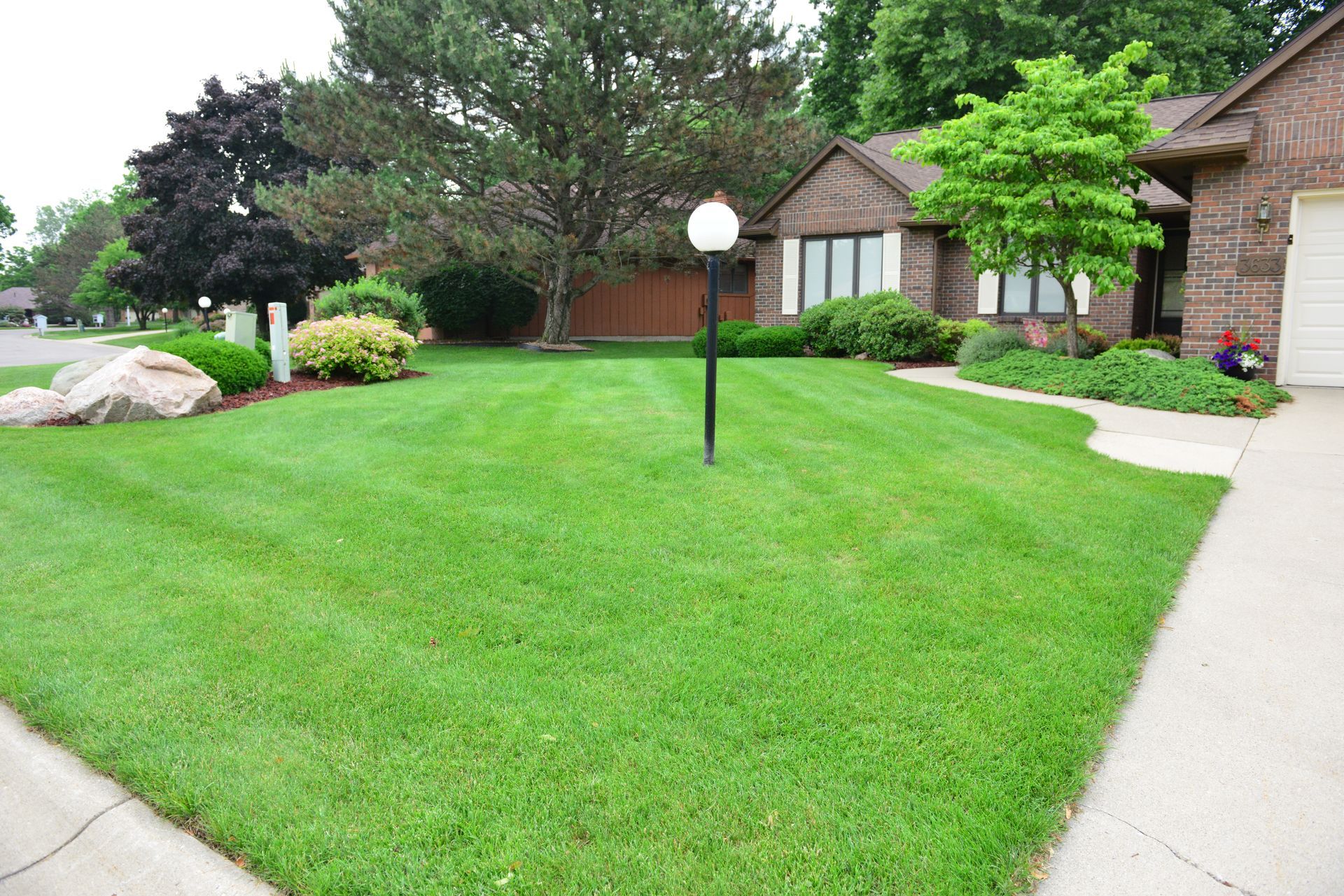 A lush green lawn is in front of a brick house.