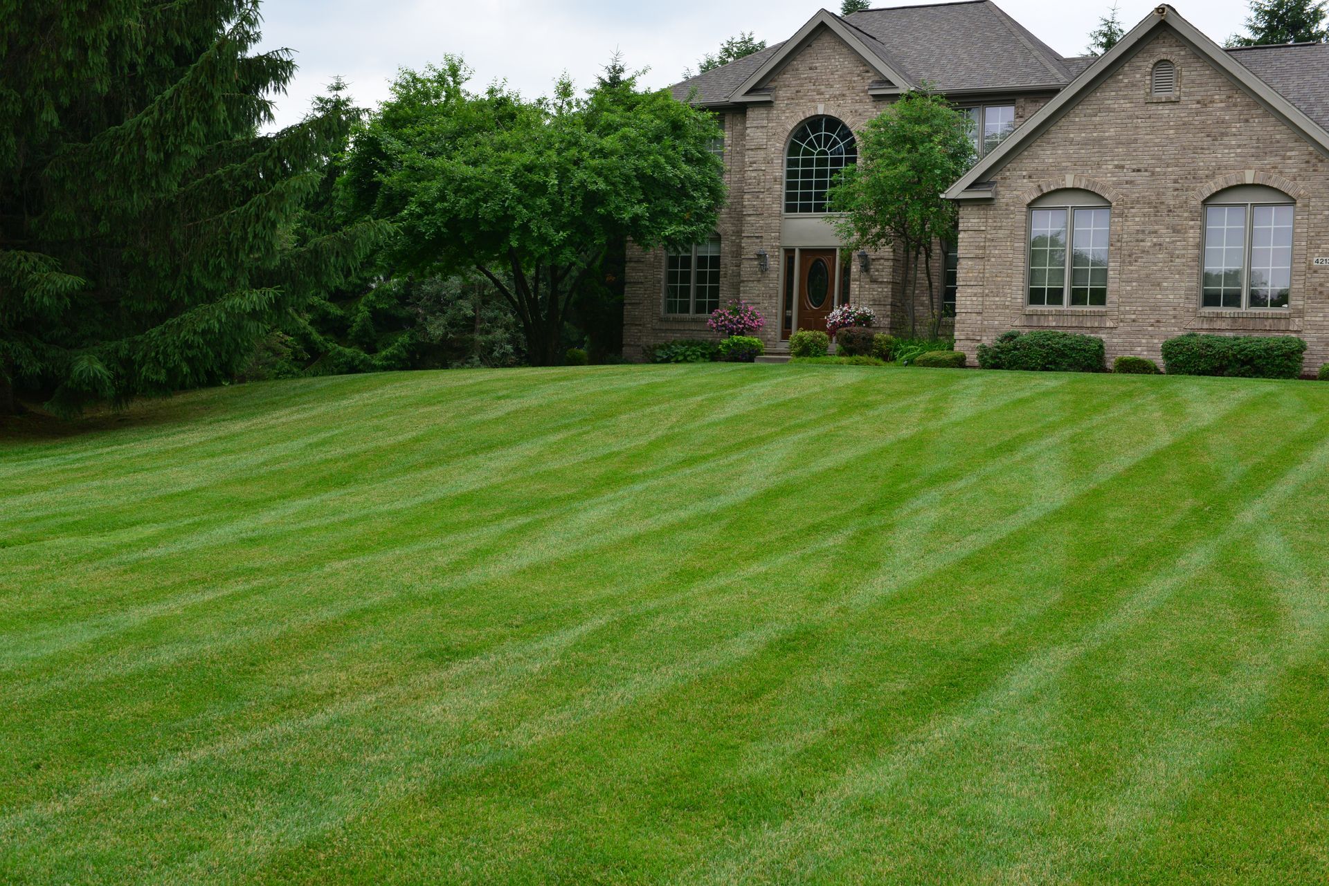 A large brick house with a lush green lawn in front of it.