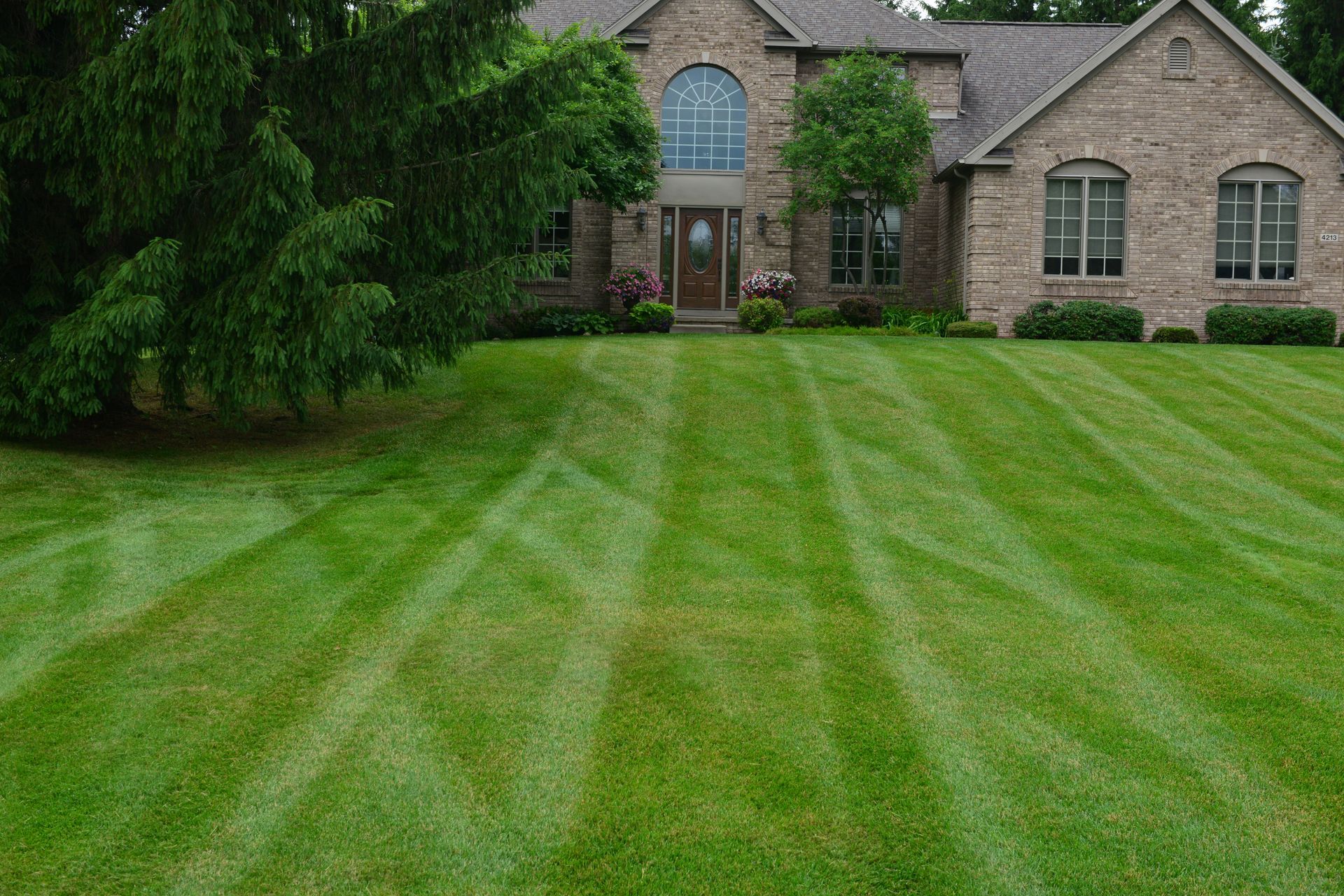 A large brick house with a lush green lawn in front of it.