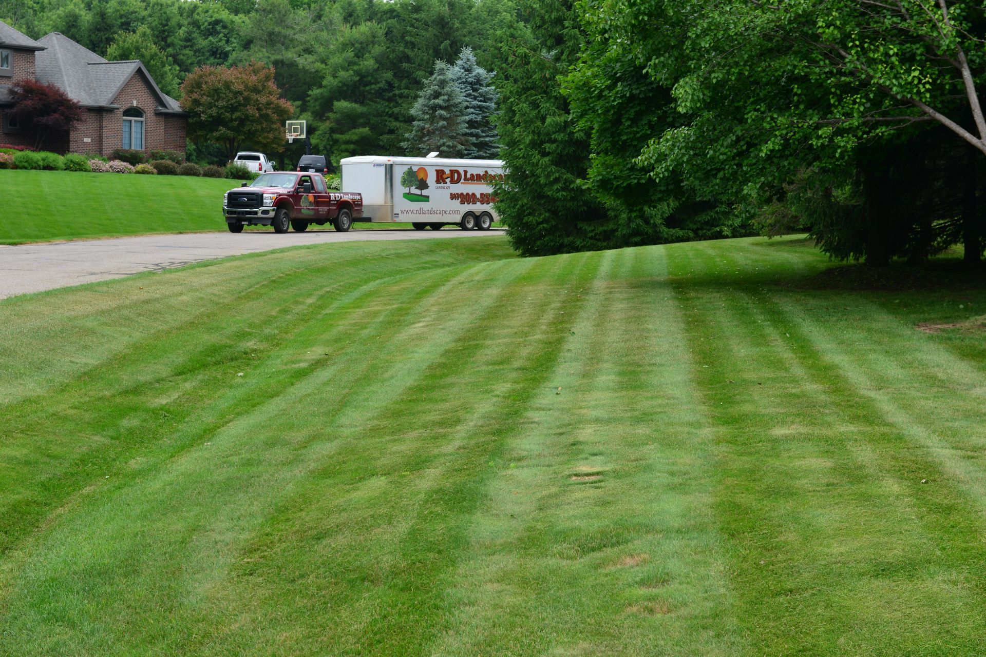 A truck is parked on the side of the road next to a lush green lawn.