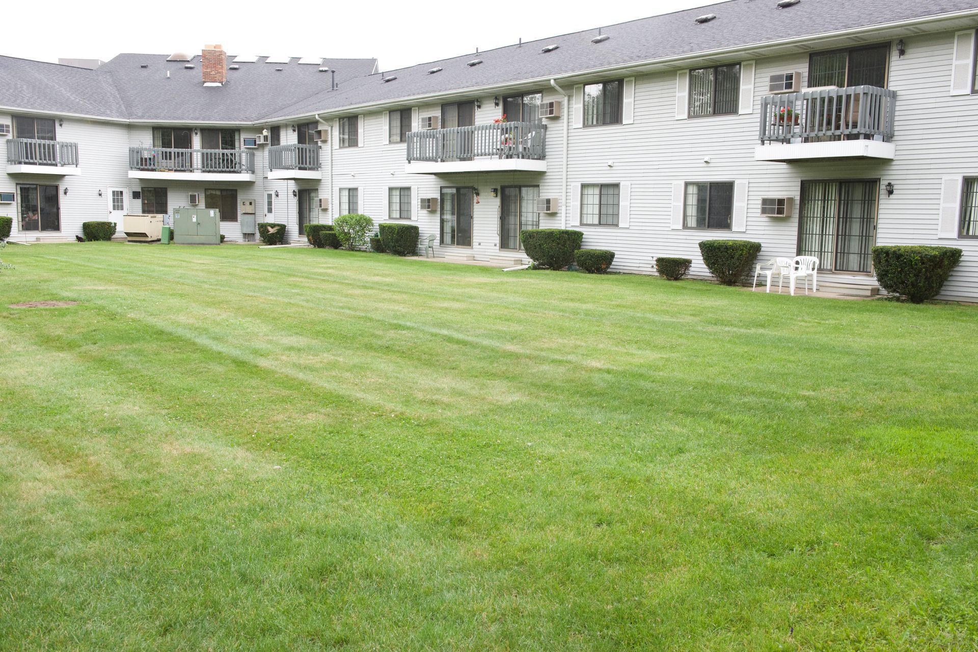 White apartment buildings with balconies overlooking a large green lawn