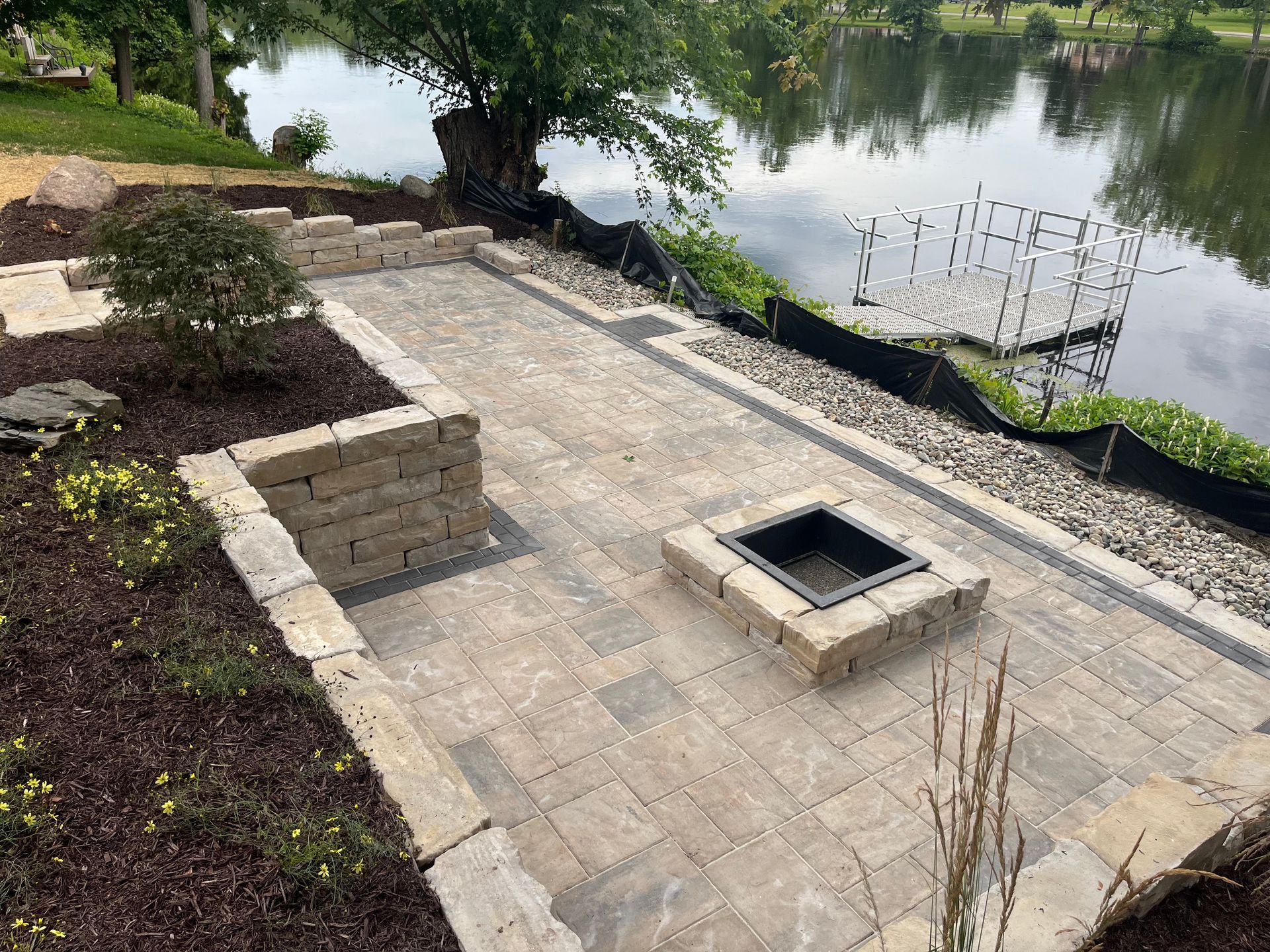 A fire pit is sitting on a patio next to a lake.