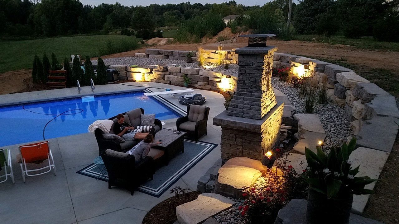 A patio area with a fireplace and a swimming pool at night.