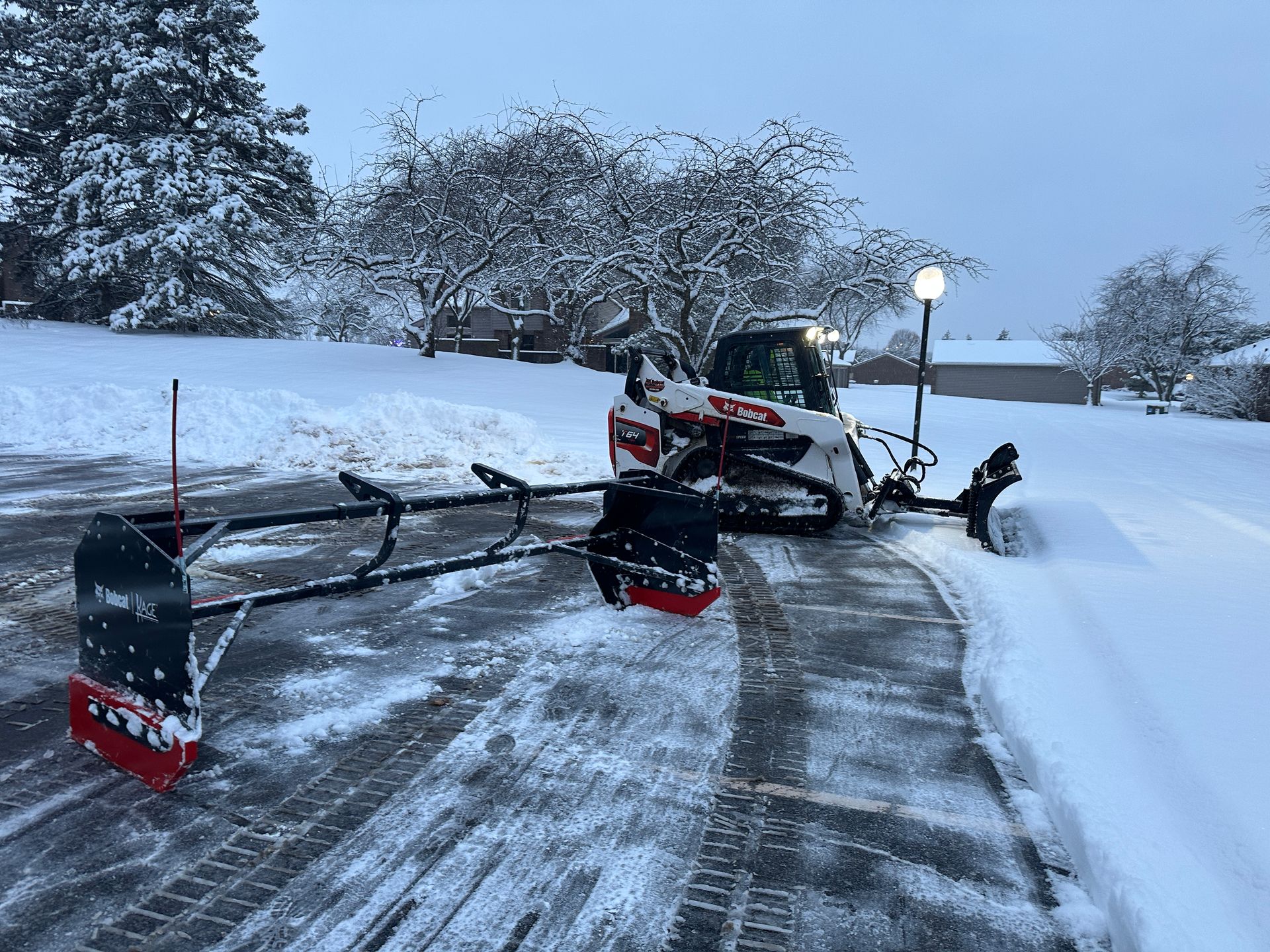 Snowblower clearing a snowy driveway beside a house at dusk