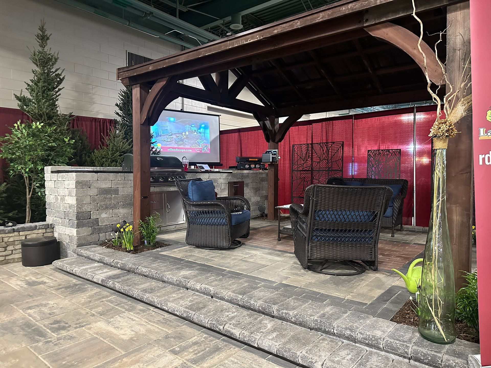 A gazebo with wicker furniture and a projector screen in a room.