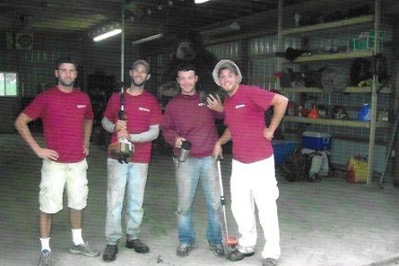 Four people in matching red shirts standing in a warehouse, posing for a photo