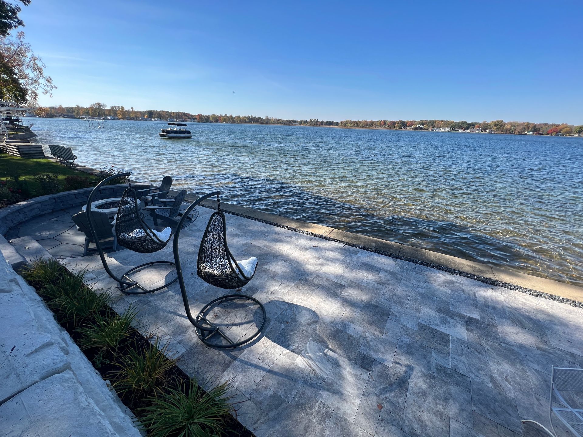 A couple of chairs sitting on a patio next to a body of water.