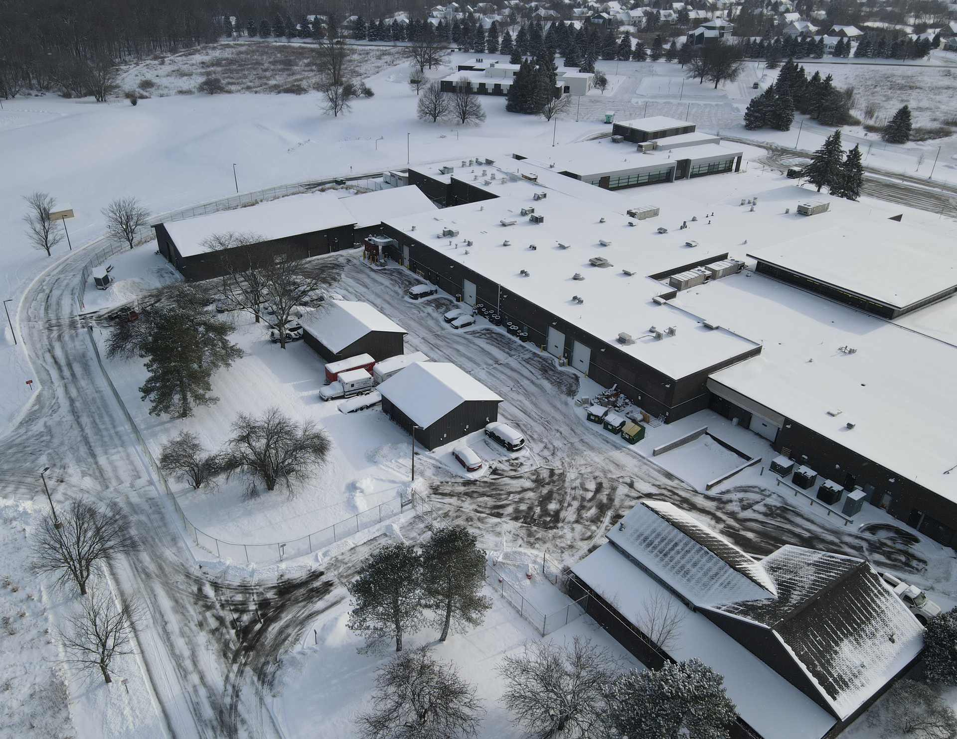 Snow-covered campus buildings seen from above, with roads and trees surrounding the complex.