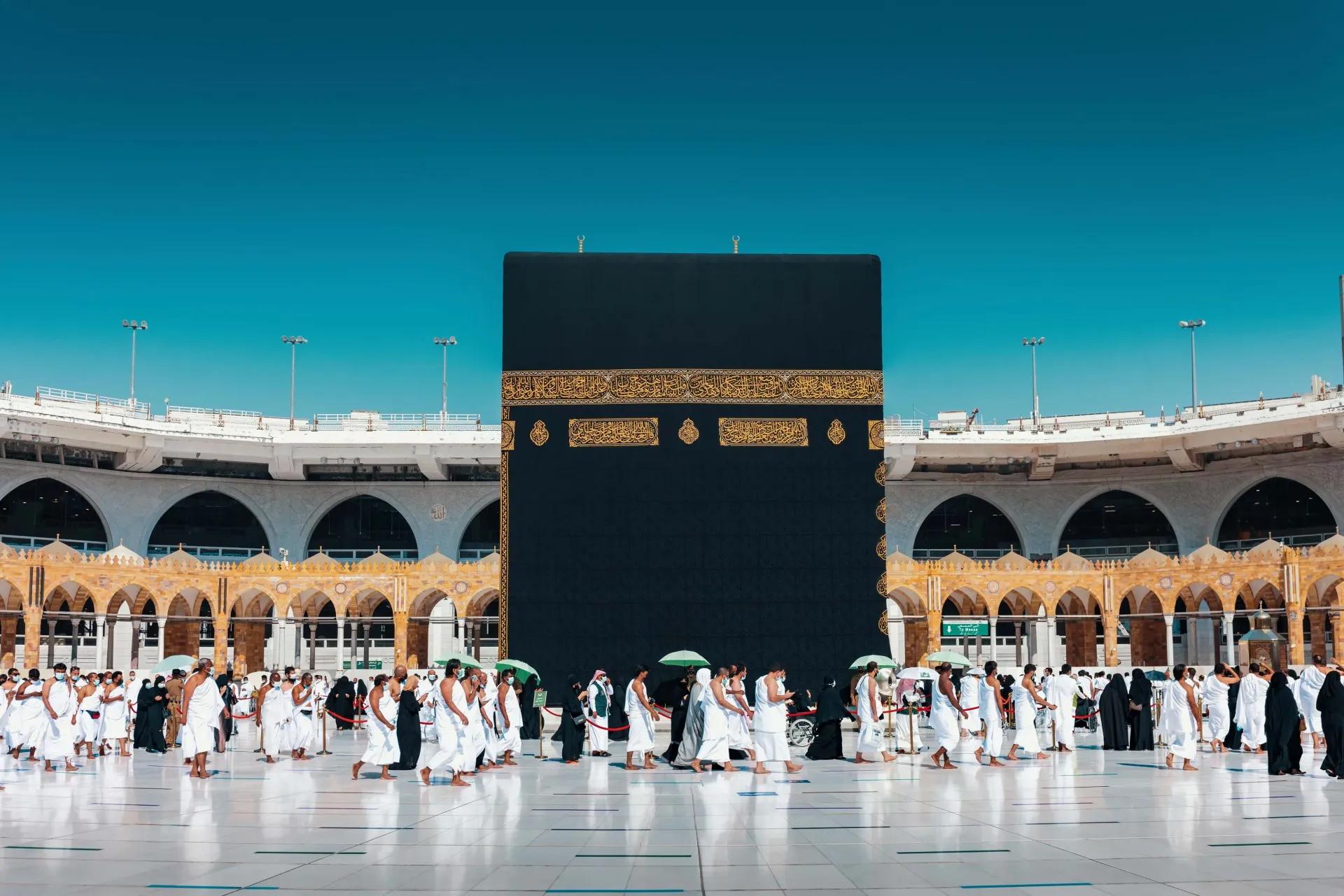 Un grand groupe de personnes est rassemblé autour de la kaaba dans une mosquée.