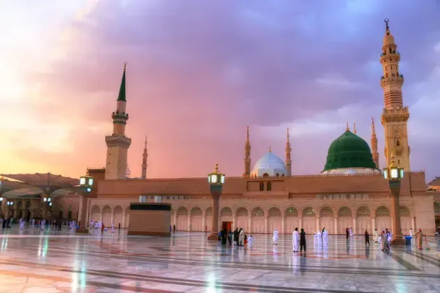 Une mosquée avec un dôme vert et un ciel violet en arrière-plan.