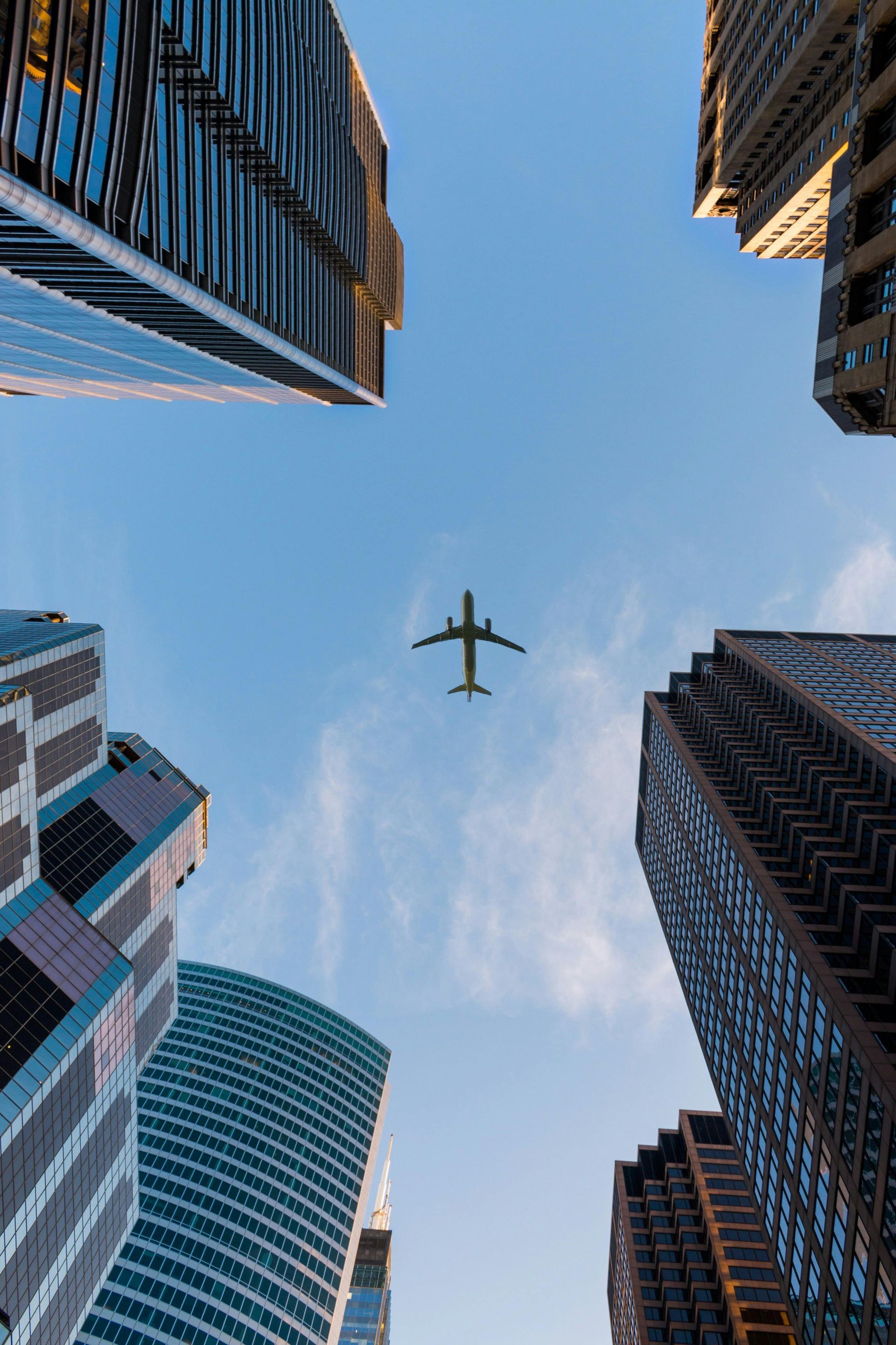 Un avion vole dans le ciel entre deux grands immeubles.