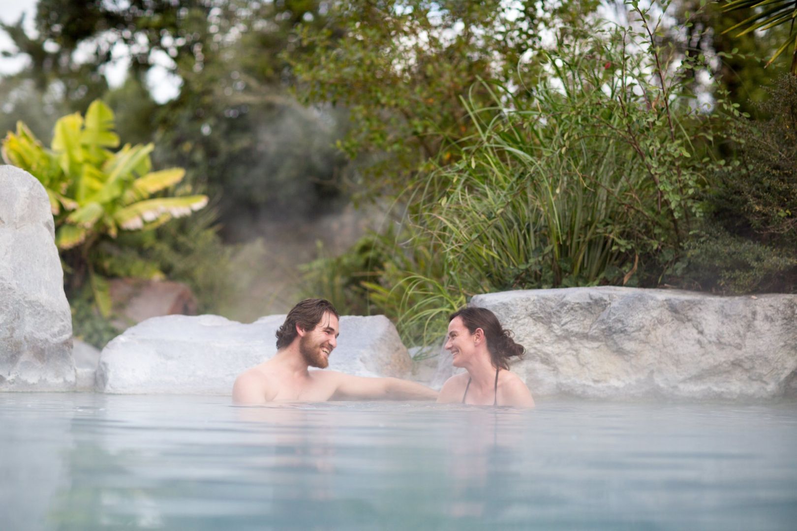 A couple relaxing in an outdoor hot pool in Taupo