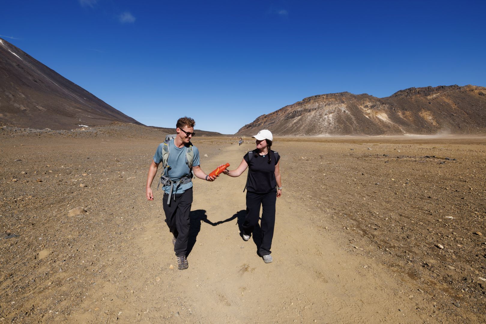 Two people walking the South Crater on the the Tongariro Alpine Crossing