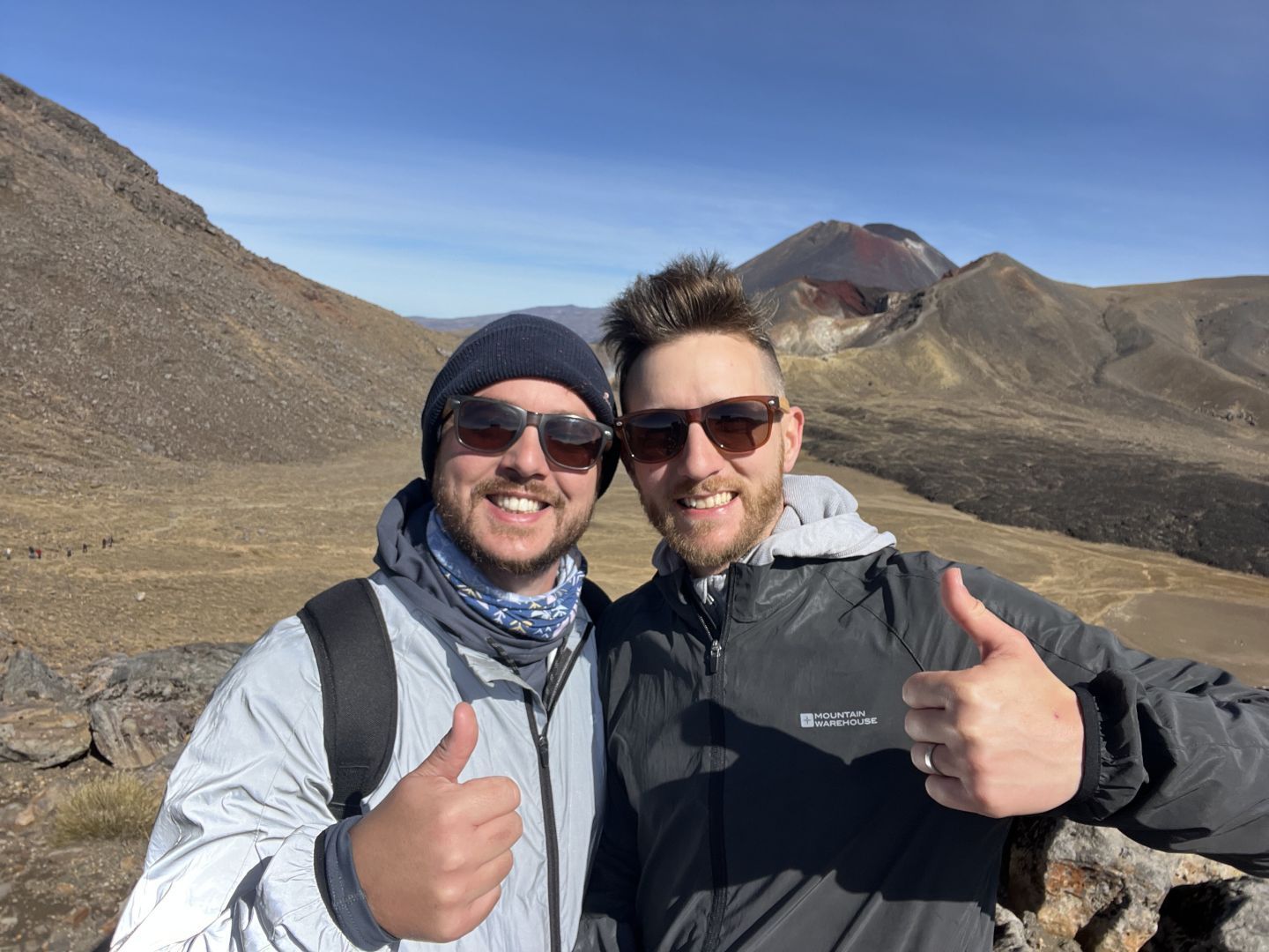 Two hiker's posing for a photo with their thumbs up midway through their hike on the Tongariro Alpine Crossing