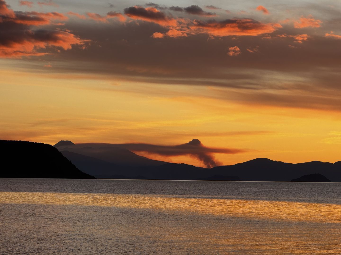 A view over Lake Taupo showing Tongariro national park on fire in the background