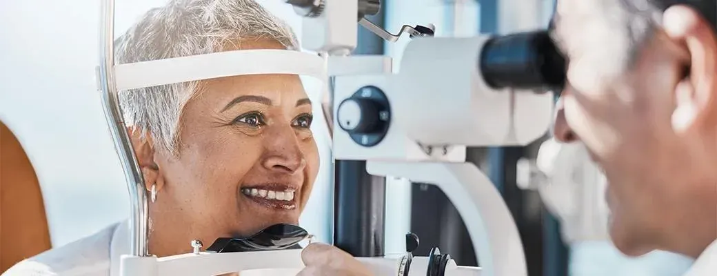 Patient smiling during an eye exam with a doctor using a slit lamp microscope