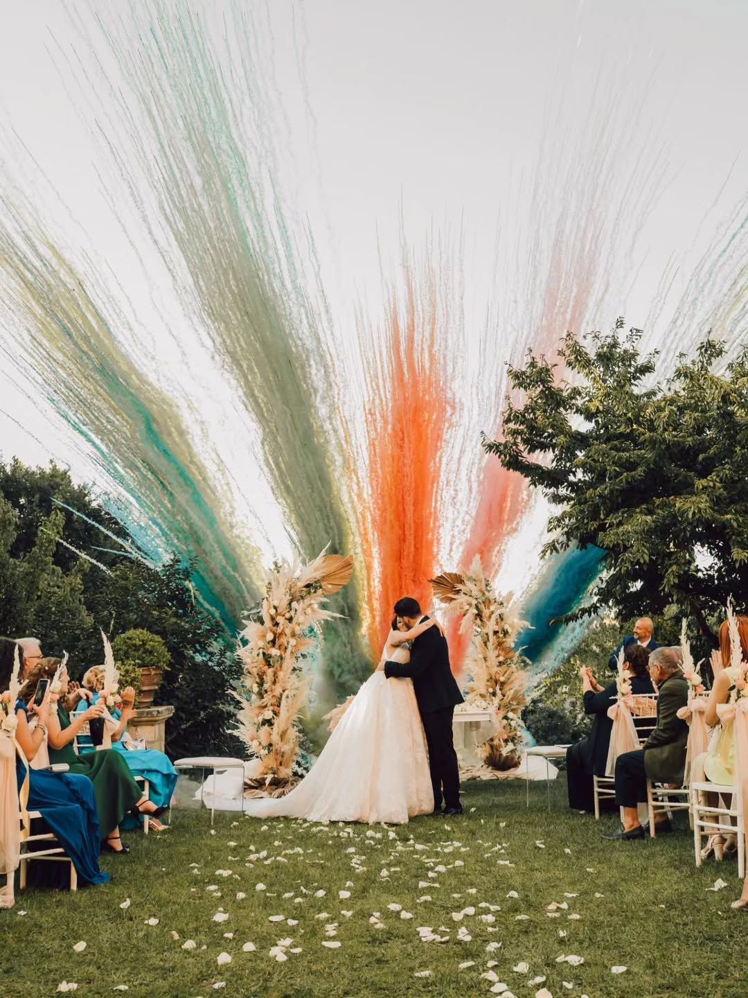 Gli sposi percorrono un sentiero di pietra fiancheggiato da fuochi d'artificio, mentre gli invitati assistono al matrimonio notturno.