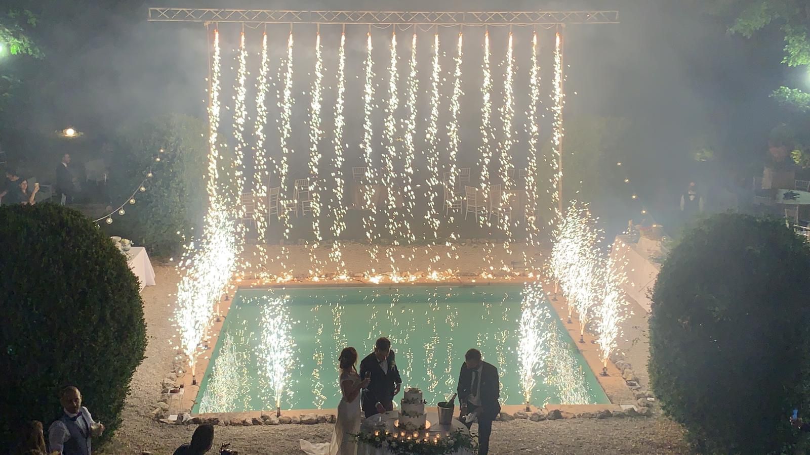 Fuochi d'artificio a cascata su una piscina durante una festa nuziale durante una celebrazione notturna.