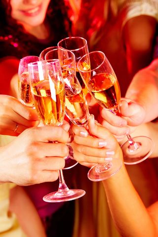 Le mani brindano con calici di champagne in un caloroso e festoso brindisi accompagnato da bevande frizzanti dorate.