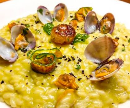 Antipasto di frutti di mare con pesce a fette, spicchi d'arancia, capperi e salsa su un piatto bianco.