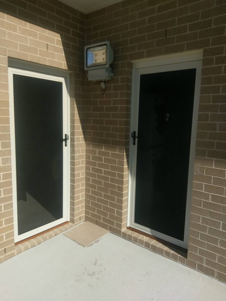 Two Screen Doors Are Sitting Next to Each Other on a Brick Wall — Everything Screendoors & More In Illawarra, NSW