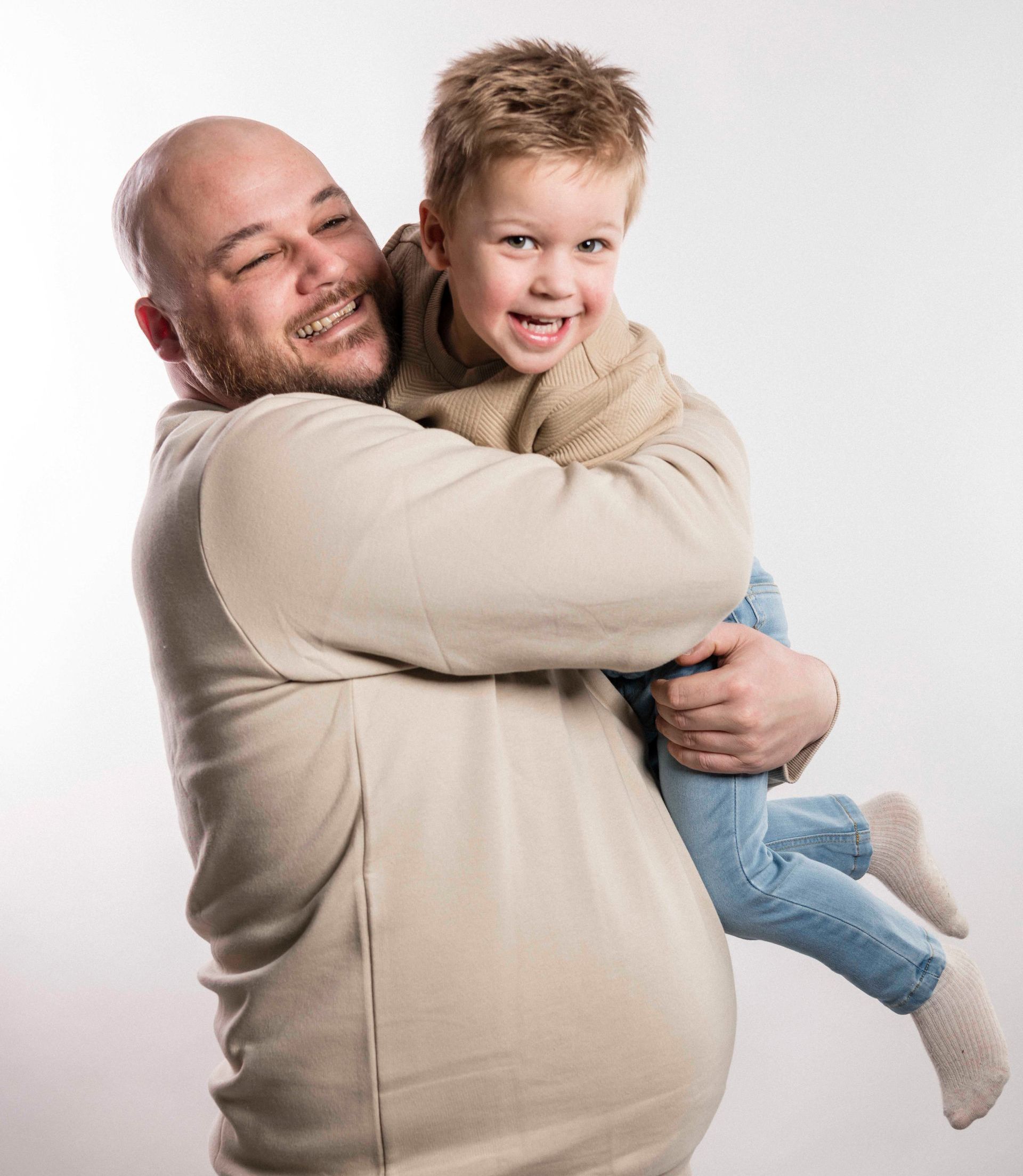 Een man houdt een klein jongetje in zijn armen.