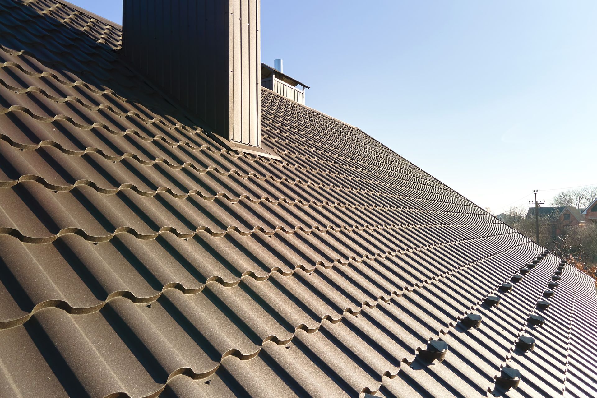 Brown Tiled Roof With Chimney Against a Blue Sky — JLH Plumbing, Gas & Roofing in Wollongong, NSW