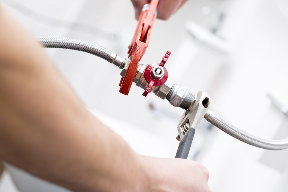 Plumber using wrenches on a faucet — JLH Plumbing, Gas & Roofing in South Nowra, NSW
