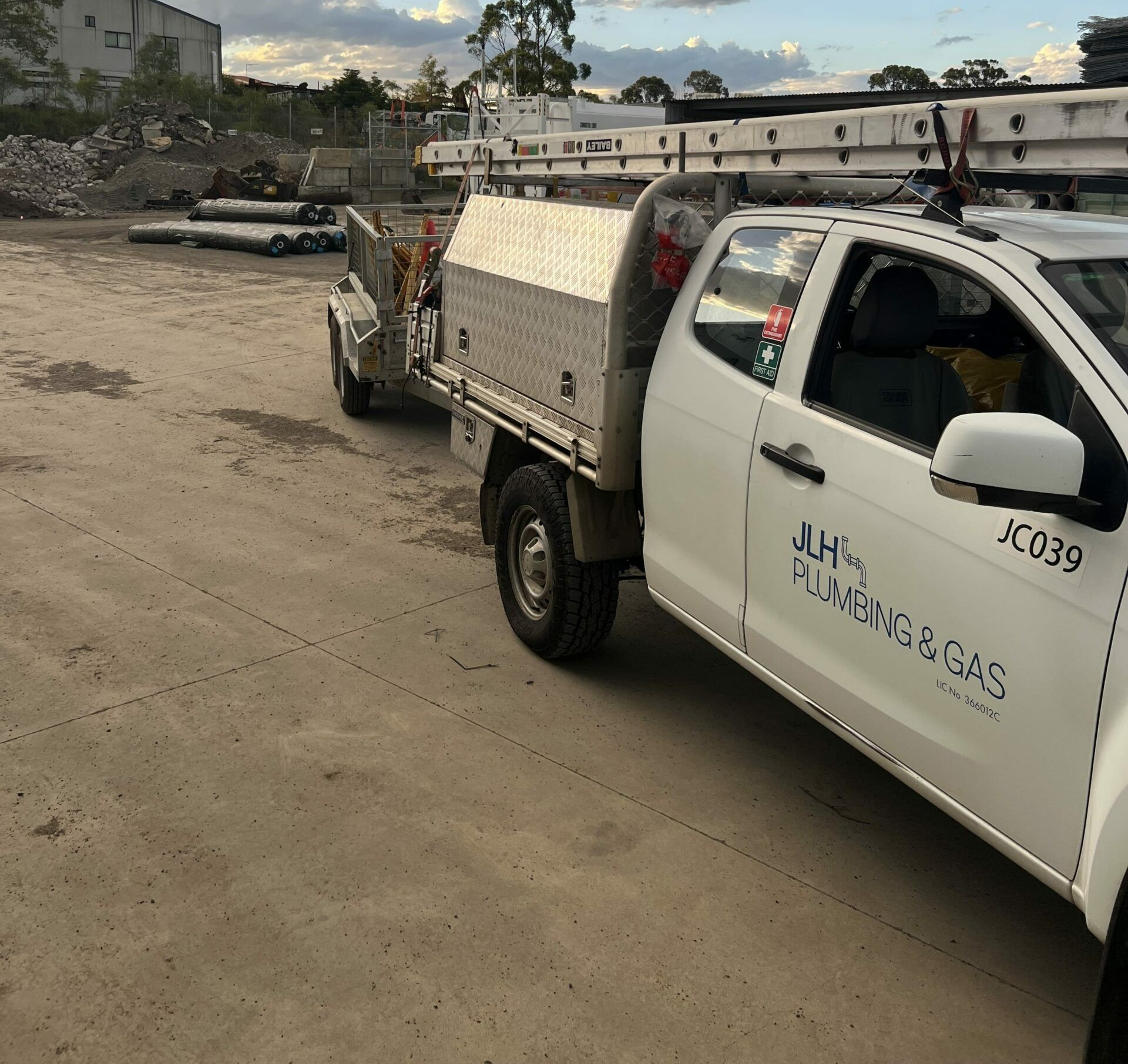 White plumbing truck with trailer in a construction site.