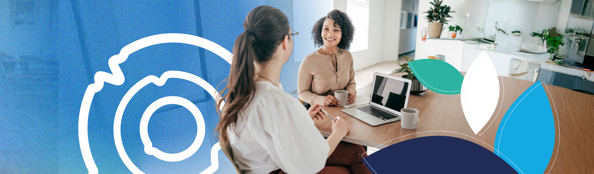 Duas mulheres estão sentadas à mesa com um laptop e conversando entre si.