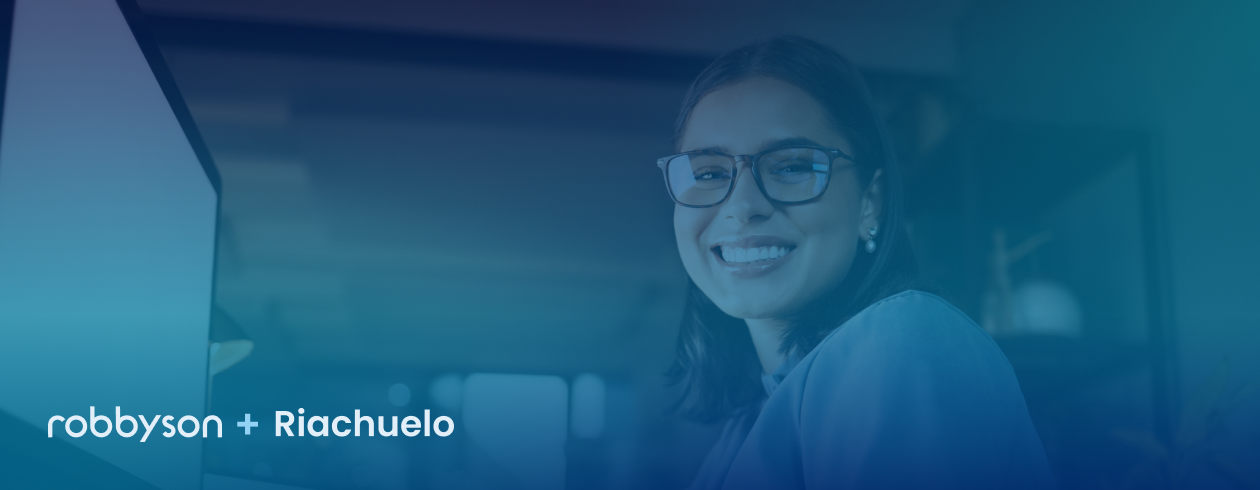 Uma mulher usando óculos está sorrindo em frente a uma tela de computador.