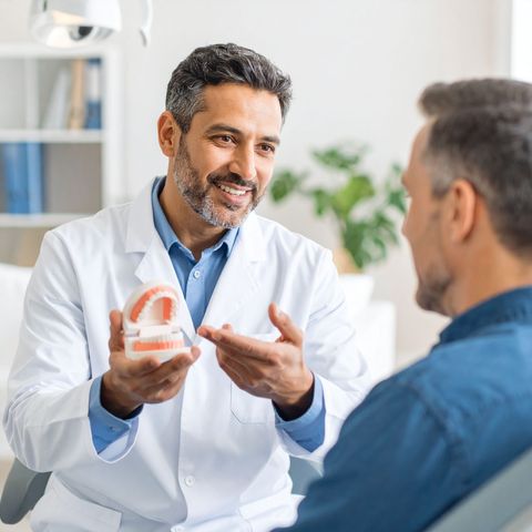 Dentist showing dentures to a patient in an office.