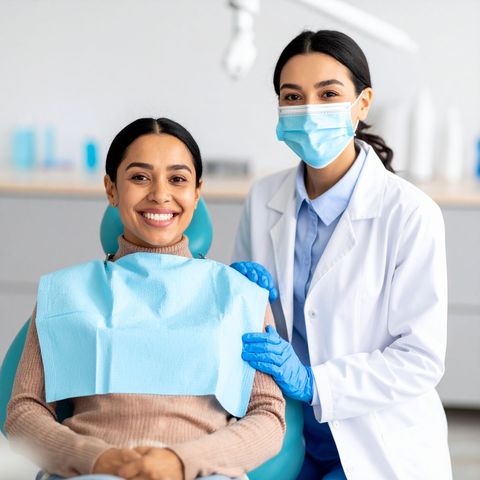 Woman smiling in dental chair with dentist, both looking at camera.