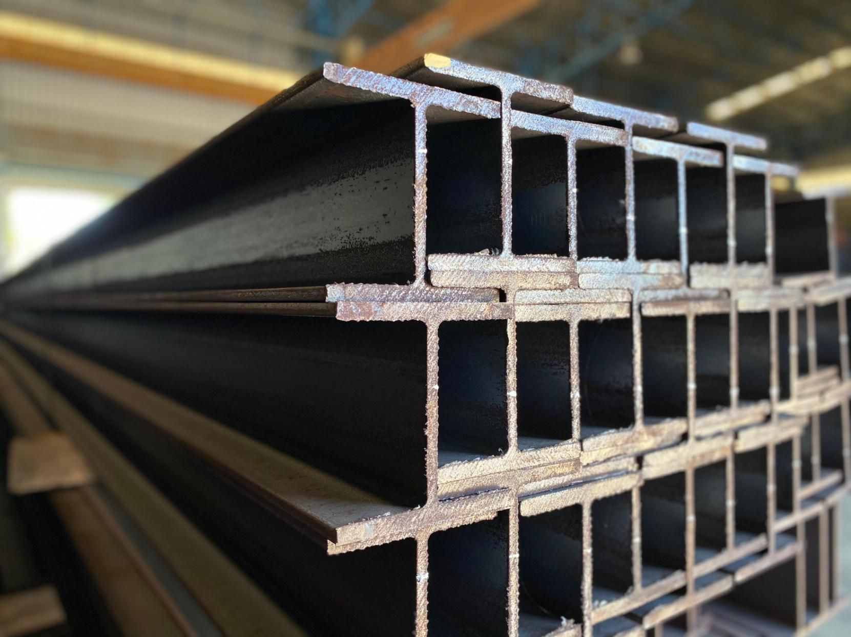 A Stack Of Steel Beams Are Stacked On Top Of Each Other In A Warehouse — Fullerton's Plumbing Manufacture In Woree, QLD
