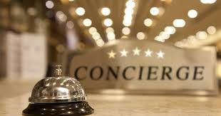 Silver concierge bell on a counter with a sign behind that reads 