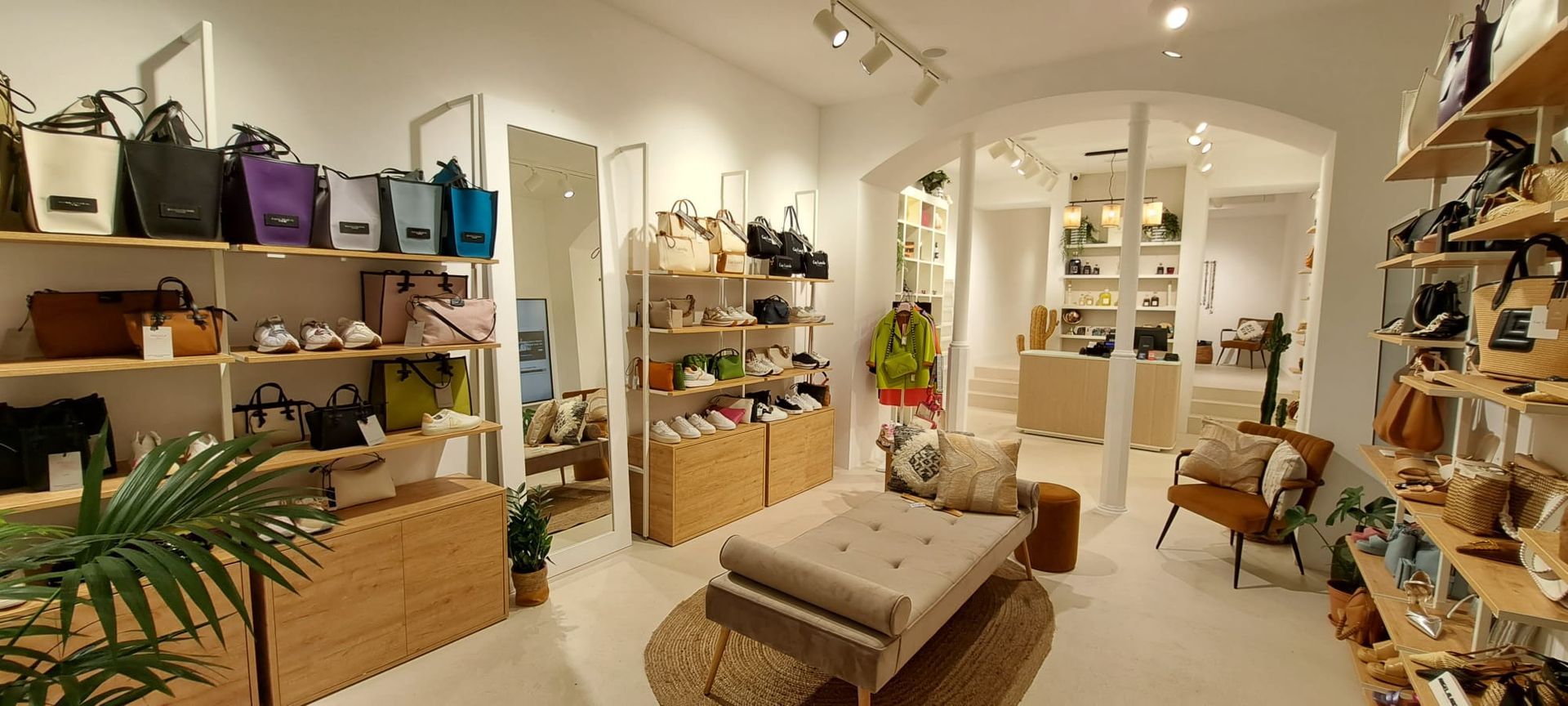 Bright, cozy boutique interior with shelves of plants, baskets, and home décor under arched doorways