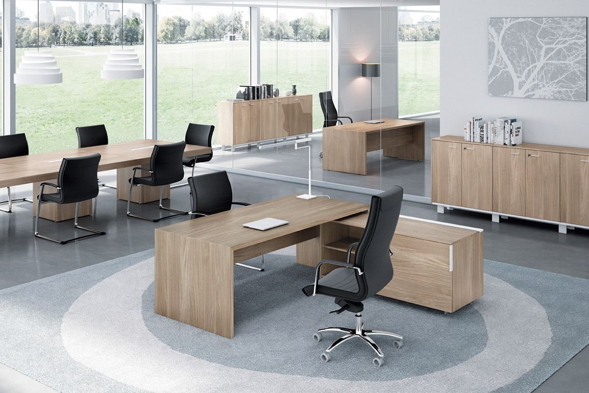 Modern office with wood desks, black chairs, and large windows in a bright open workspace