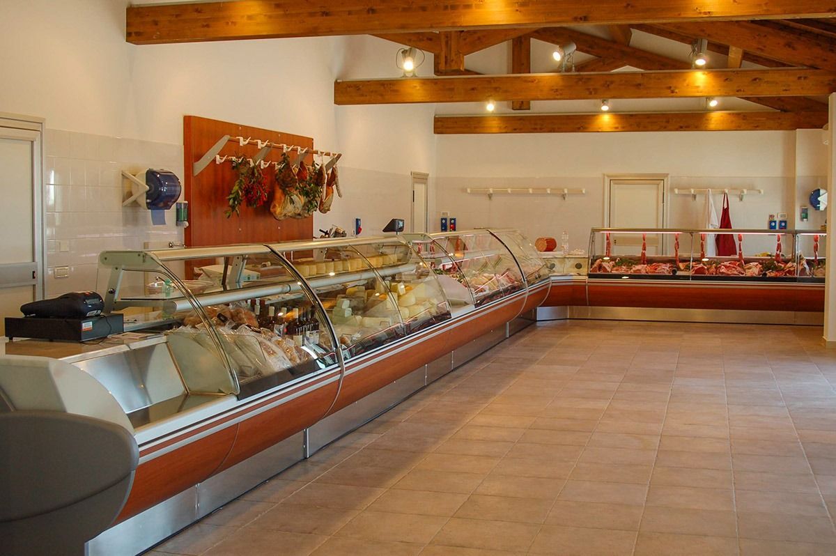 Bakery display case with pastries in a bright room with wooden beams and tiled floor