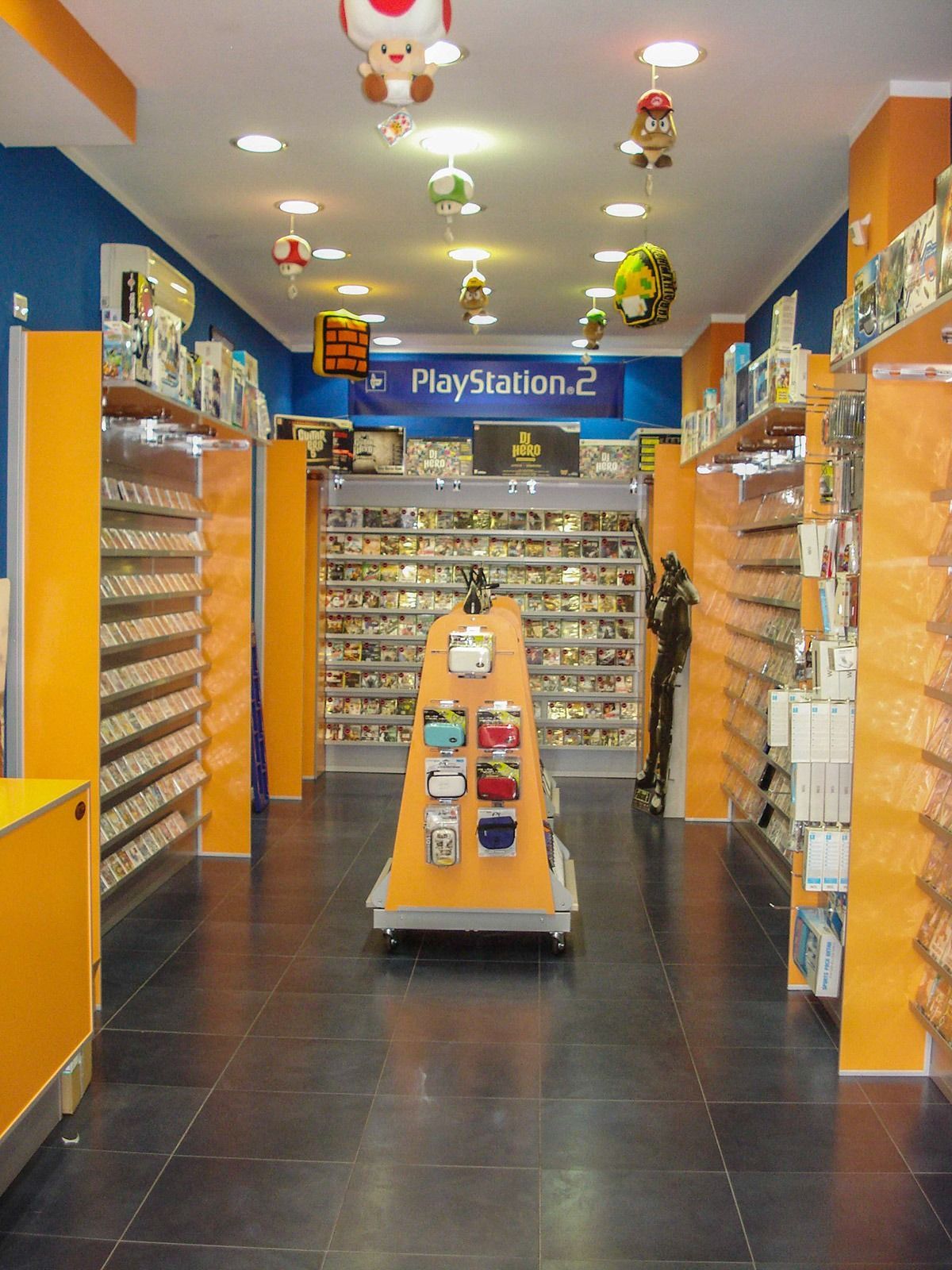 Interior of a PlayStation 2 game store aisle with shelves of video games and a display stand