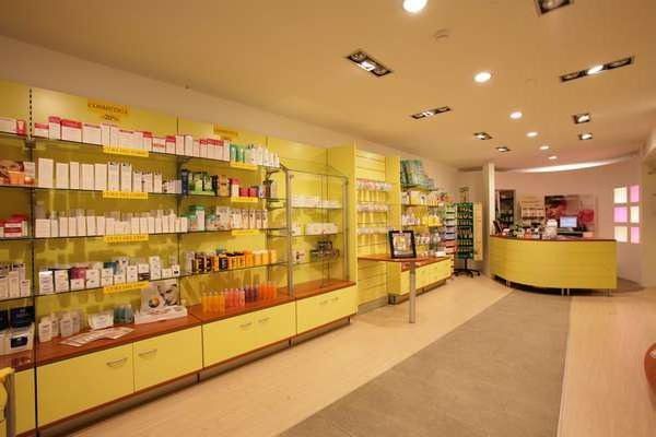 Bright pharmacy interior with yellow shelves of products and a curved front counter