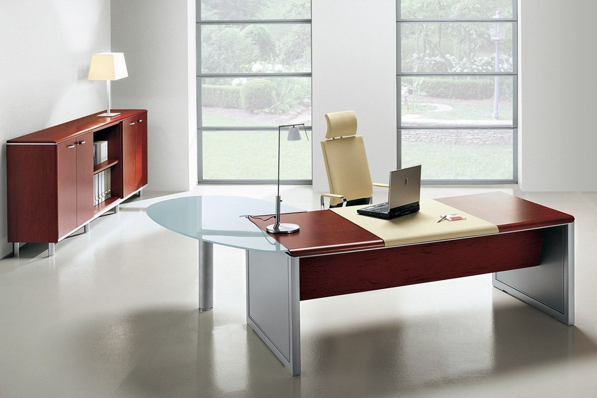 Modern office with a red desk, cabinet, lamp, and two large windows showing a bright view.