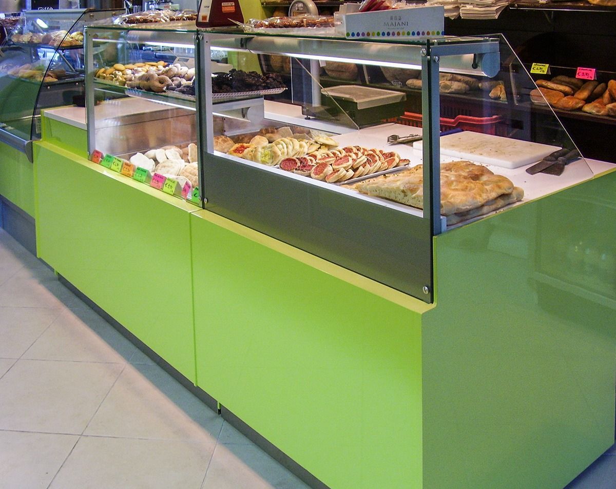 Green food display counter with trays of pastries and cakes behind glass in a cafe or bakery