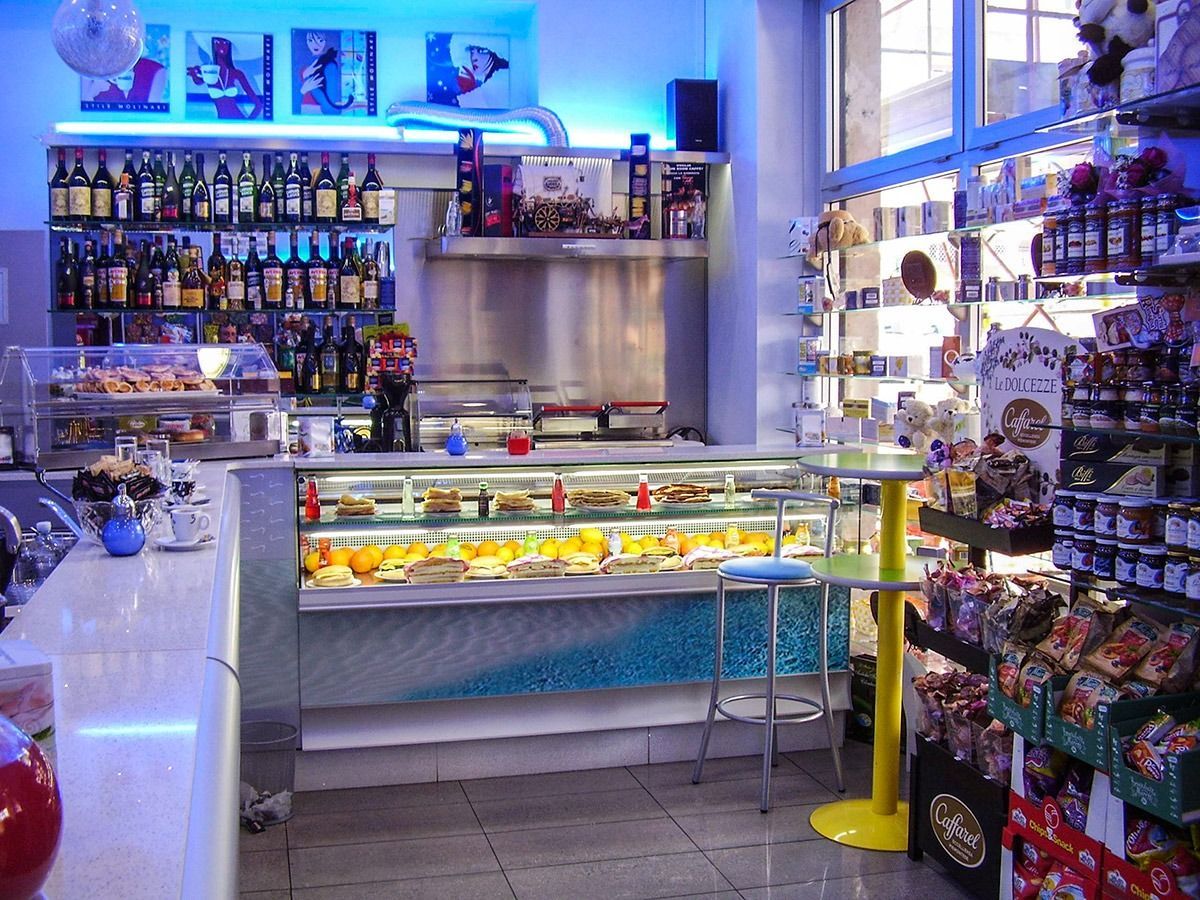 Bright candy shop with glass display case, colorful sweets, bottles, and hanging treats under blue lighting