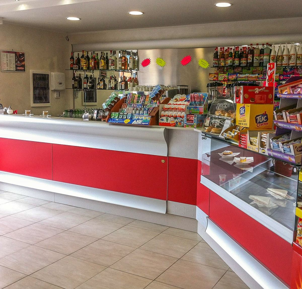 Bright red-and-white snack counter in a convenience store with candy, drinks, and glass display cases